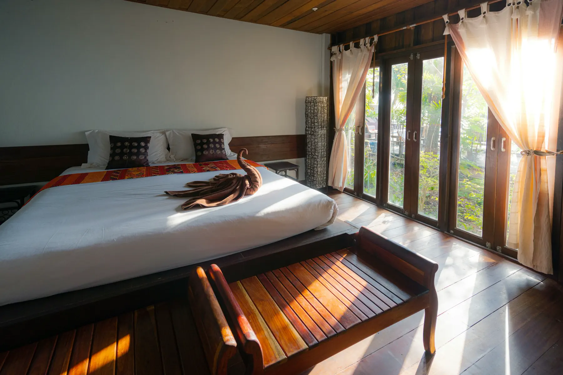Unsplash Sunlit hotel suite with taut white linen and a folded towel presentation — editorial still