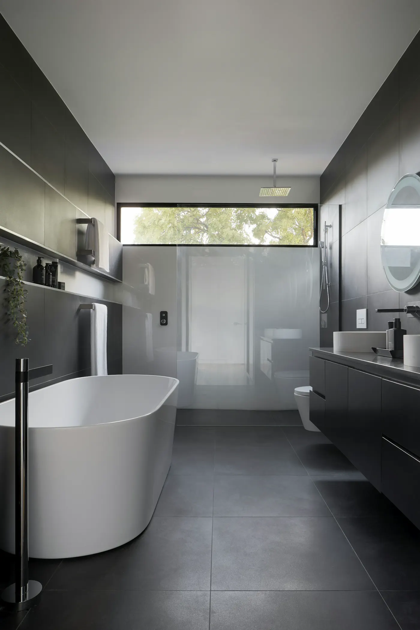 Unsplash Dark-stone hotel bathroom with a freestanding tub, dual vanity, and walk-in shower — editorial still